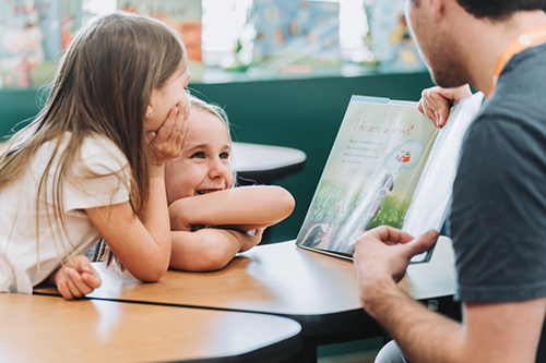 Teacher reading a book to two girls