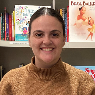 Staff member smiling for photo in brown sweater 