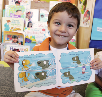 Young boy student holding an open book