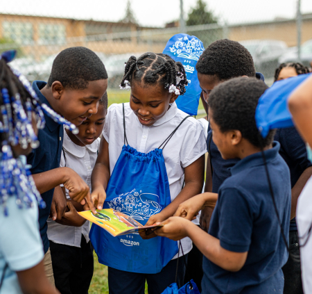 Kids huddled outside together reading books