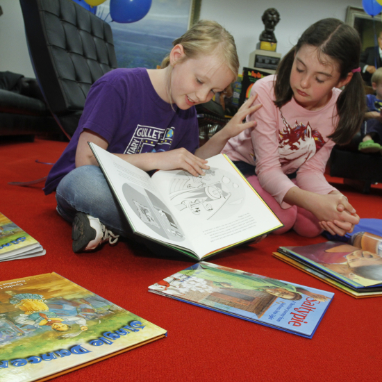 2 girls reading books on the floor