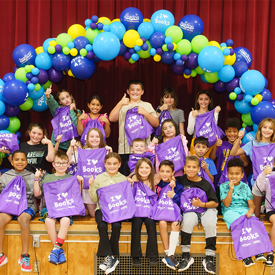 Kids holding up RIF tote bags