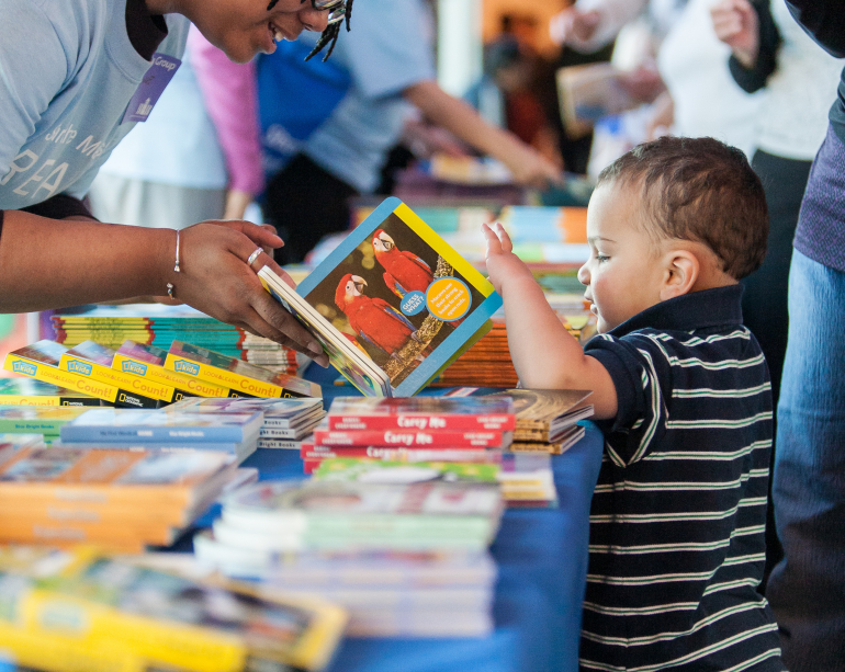 Children boy far away at book selection table RIF event