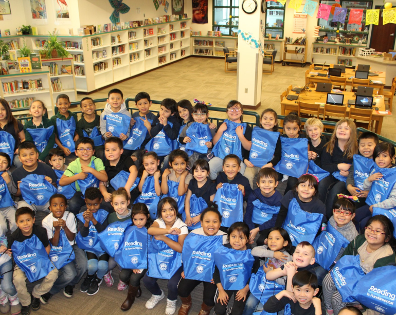 Group of students holding RIF bags reading literacy
